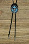 Close Up View Western Style Black Braided Leather Bolo Tie with beautifully detailed steer skull slide in grey and matt black and turquoise southwest enamel design. 