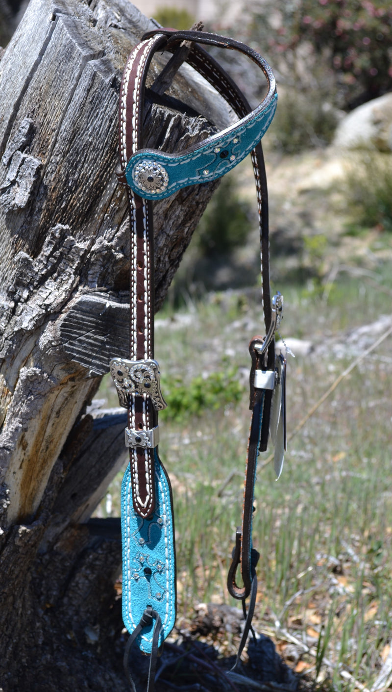 3/4" Memphis One Ear Headstall.  Made from dark brown leather with heavy white stitching.  Part of the Weaver Leather Common Threads Collection.   Cheek and ear piece have a turquoise suede leather overlay with stitched cross motif.  Genuine Swarovski crystals adorn the headstall and buckles.  Black tumbled leather ties at the bit ends.