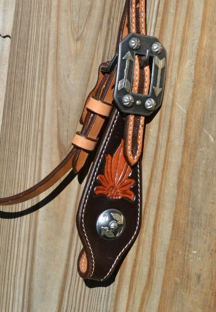 Close Up View Bit end ...  Wide browband headstall with Sunflower Tooling with two-tone chocolate colored leather and natural tooling.  Accented with arrow motif double adjustment buckles and leaf conchos.     Actual headstall differs slightly from manufacturer canned photo.  Headstall shown in live photos is the one you will receive with the arrow buckles.  Horse size.