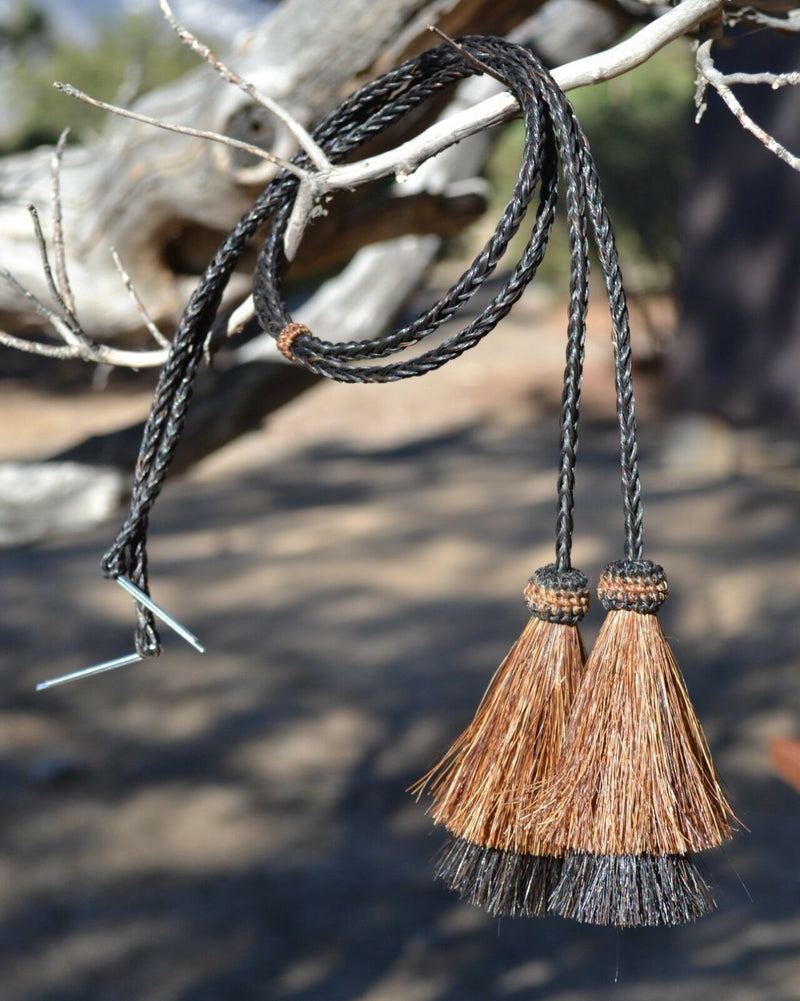 Close Up View natural horse hair Stampede String with two bell mule tail cut tassels and cotter pin attachments.     Black/Chestnut/Black