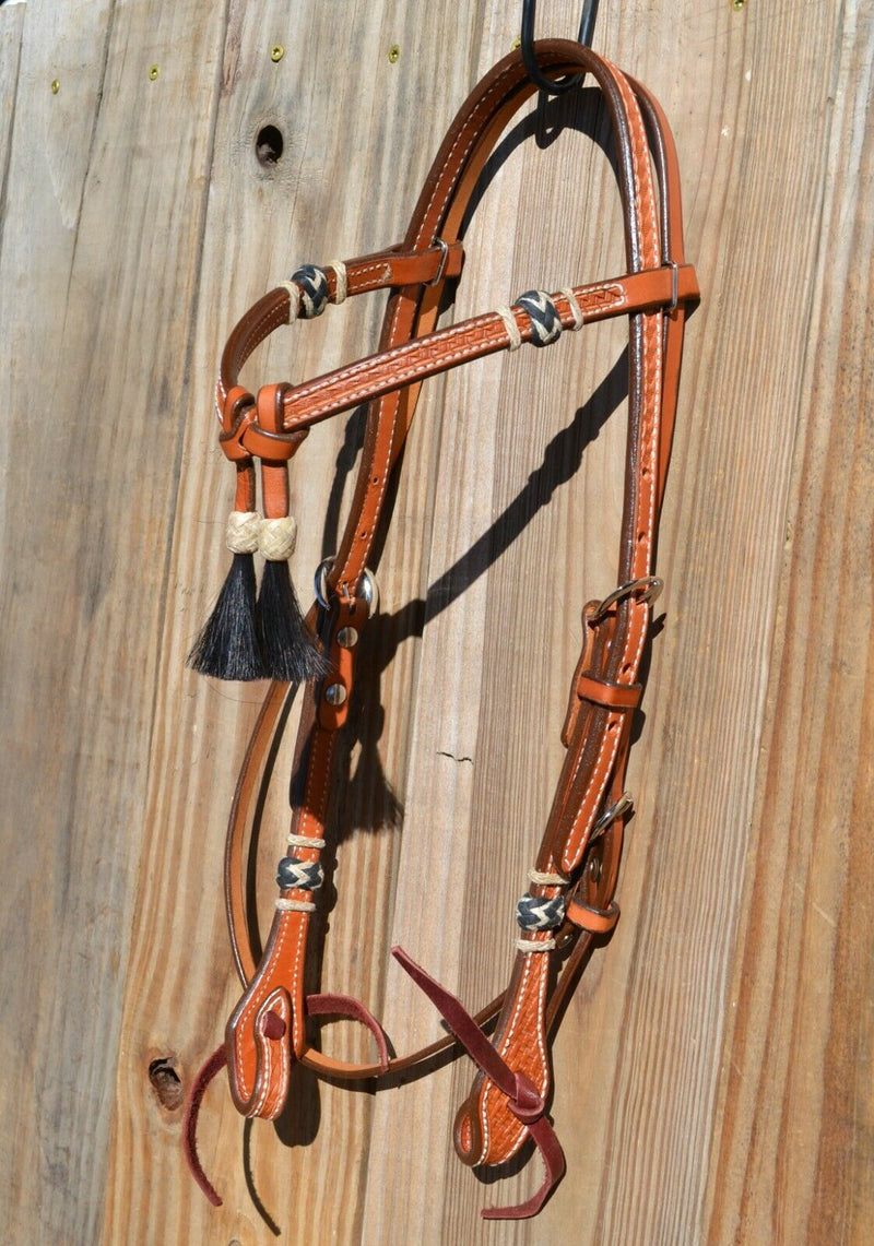 5/8" Futurity / Cross-Over Browband Headstall with black horse hair tassels and natural/black rawhide buttons.     Made from two-ply and stitched regular oil leather with removable stainless steel buckles that are adjustable on both sides and latigo ties at bit ends