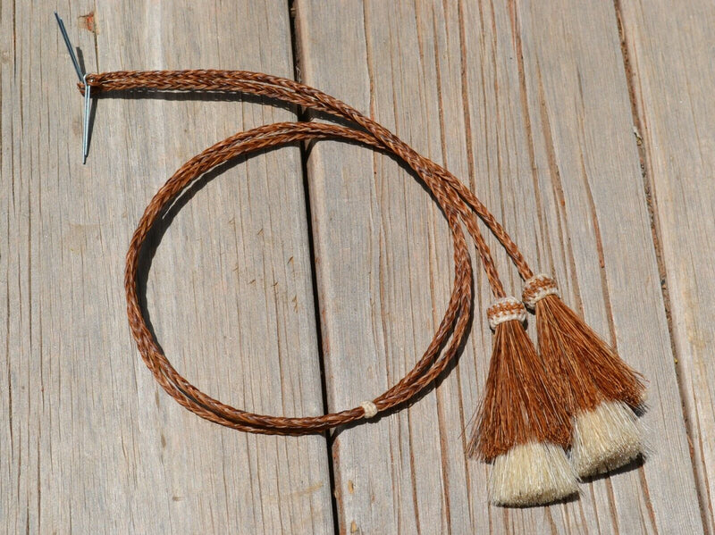 Close Up View natural horse hair Stampede String with two bell mule tail cut tassels and cotter pin attachments.     Chestnut/Chestnut/White
