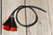 Close Up View natural horse hair Stampede String with two bell mule tail cut tassels and cotter pin attachments.    Black/Red