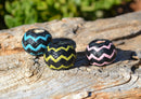 Various Colors Hand braided rawhide scarf slide.  Custom made in two-tone combinations of black and bright colored leather braided in a "zig zag" pattern.