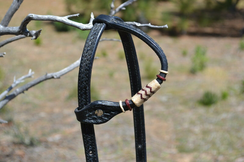Close Up View Single Ear Jose Ortiz 5/8" One Single Ear Headstall.  Constructed of two-ply and stitched black finished leather.  Hand carved with Jose's signature basket weave tooling and natural hand braided rawhide with burgundy latigo details on cheek pieces and ear pieces.   