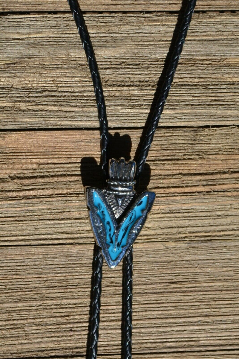 Close Up View Western Style Black Braided Leather Bolo Tie with beautifully detailed arrow head slide in silver and matt black and turquoise southwest enamel design.  Bolo has silver colored tips. 