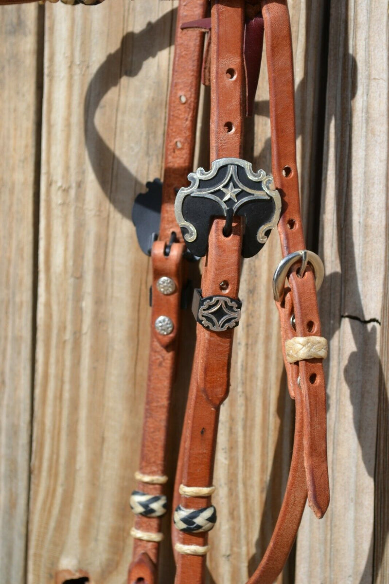 Close Up View Buckle Jose Ortiz 5/8" Shape Browband Headstall.  Constructed of super soft conditioned natural harness leather.  Jose's signature natural hand braided rawhide with black details on cheek pieces and browband.