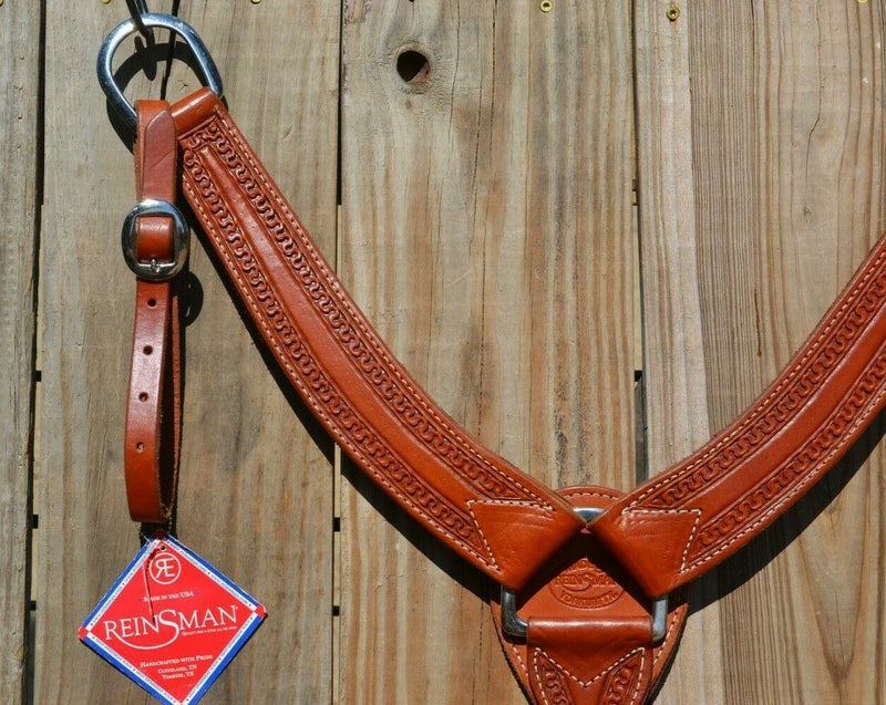 Close Up View Reinsman Heavy Duty 2" Double Ply Leather Breast Collar with Hand Carved with Snake border tooling.  The chest pieces are swept upwards like a martingale style breast collar for less restrictive shoulder movement, however, it has standard tugs.  Medium honey color leather.  