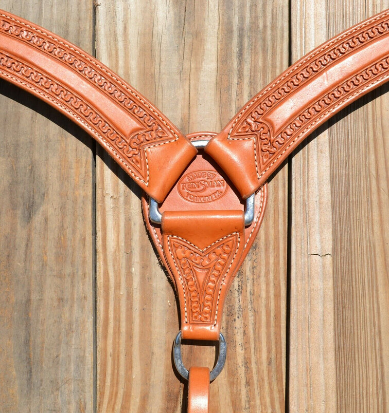 Close Up View Reinsman Heavy Duty 2" Double Ply Leather Breast Collar with Hand Carved with Snake border tooling.  Light honey color leather.  Stainless steel hardware and tugs and cinch drop.   1" x 12" adjustable tugs. 