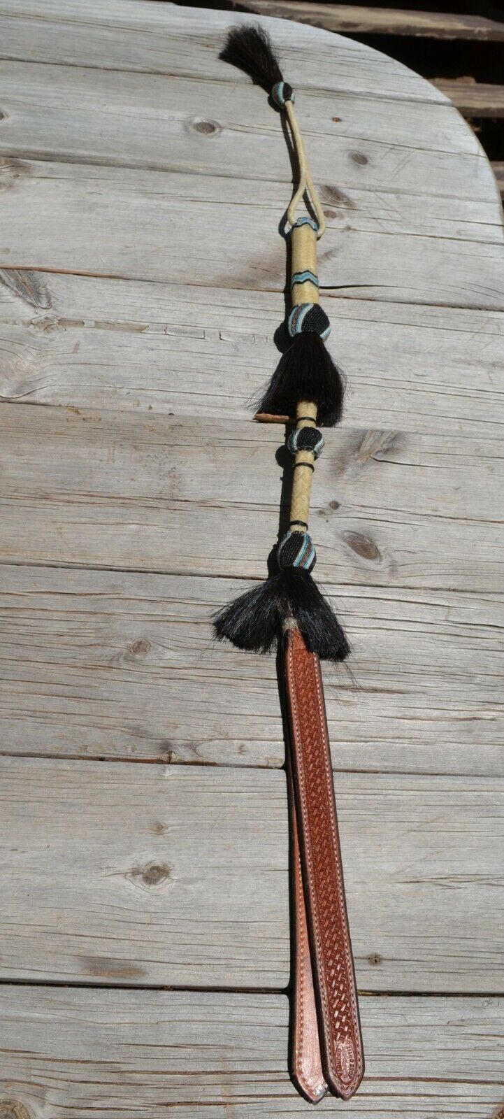 Beautiful Jose Ortiz  Braided Rawhide Quirt Whip with Hitched Horsehair Knots, black horsehair tassels and Hand Tooled Leather Popper.   Natural colored rawhide with turquoise blue, tan and black details. 