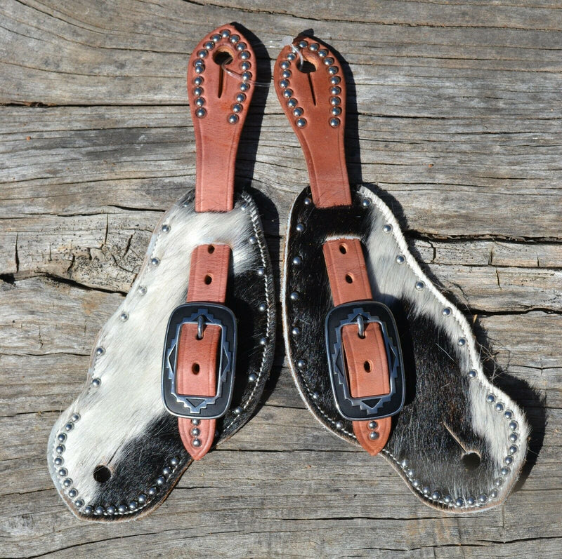 Front View Cowboy Style Hair-On Cowhide Shaped Spur Straps.  Hair-on cowhide with black & white coloring with stainless steel spots.  Soft distressed leather lining and Hermann Oak harness leather straps. 